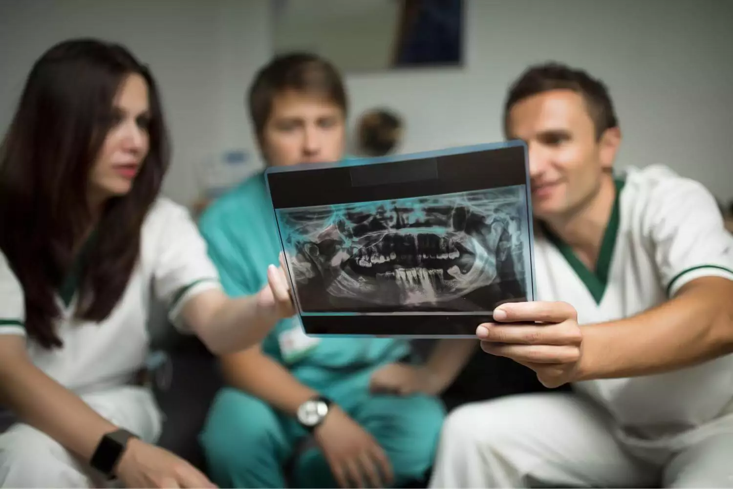 A team of dental implant specialists analyzing a patient's panoramic X-ray to assess bone density and determine optimal placement of titanium implants in the jawbone, ensuring osseointegration and long-lasting stability for dental implant-supported crowns or bridges as part of a full mouth reconstruction.